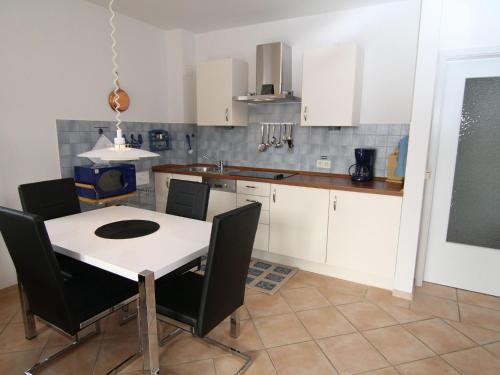 une cuisine avec une table blanche et des chaises noires dans l'établissement Apartment, St Peter-Ording, à Sankt Peter-Ording