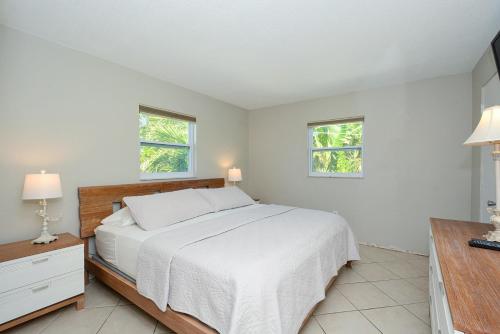 a white bedroom with a bed and two windows at Canal 315 - Right in Siesta Key Village! in Siesta Key
