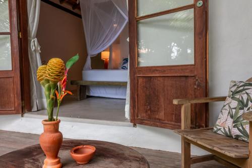 a vase with a flower on a table next to a door at DA GRAÇA HOTEL in Trancoso