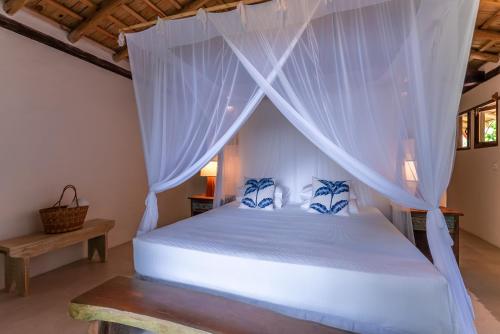 a bedroom with a white bed with mosquito netting at DA GRAÇA HOTEL in Trancoso