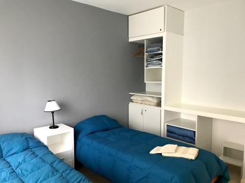 1 dormitorio con 2 camas azules en Cabañas Sendero de Pinos - Alquileres RV en Monte Hermoso