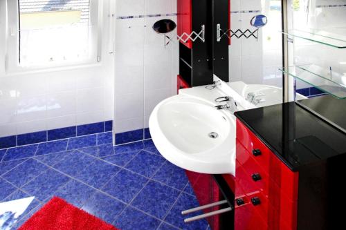 a bathroom with a white sink and red cabinets at Ferienhaus Adler in Mirow in Mirow