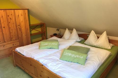 a large bed with two green pillows on it at Ferienhaus Rhönblick, Kaltensundheim in Kaltensundheim