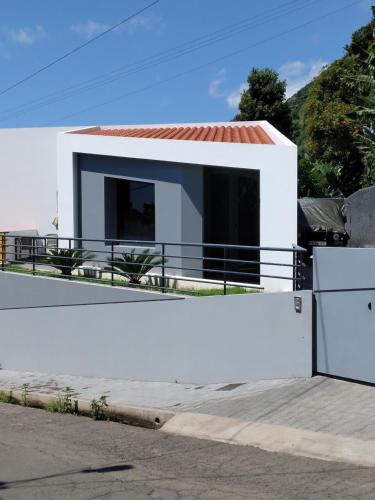 Biały dom z czarnymi oknami i białym płotem w obiekcie Anjos's Choice w mieście Ponta do Sol