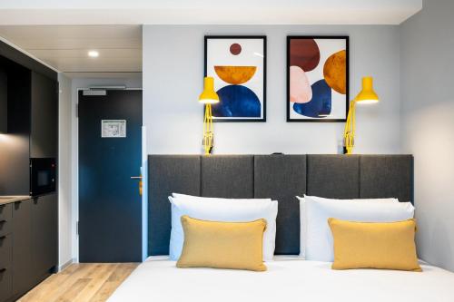 a bedroom with a bed with two yellow pillows at Staycity Aparthotels Frankfurt Airport in Frankfurt/Main