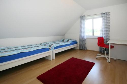 a bedroom with a bed and a desk and a red chair at Holiday home Barbara, Zarrentin in Zarrentin