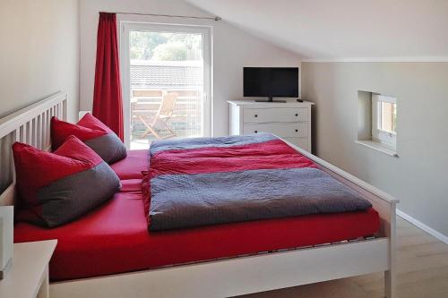 a bedroom with a bed with red sheets and a window at Vacation home Bel Ami, Nakenstorf in Nakensdorf