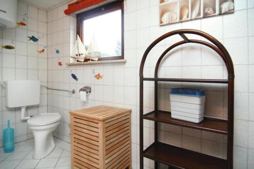 a bathroom with a toilet and a window and a shelf at Cottage, Dolgen am See in Klein Sprenz