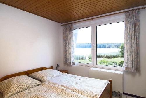 um quarto com uma cama e uma grande janela em Double bungalow at the Groß Labenzer See, Klein Labenz em Klein Labenz