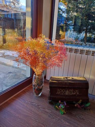 a vase with flowers in it next to a window at Hotel FAMIL - adults only in Bansko