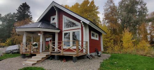ein rotes winziges Haus mit einer Veranda in der Unterkunft Uusi Saunamökki Jämsässä, lähellä Himosta in Jämsä
