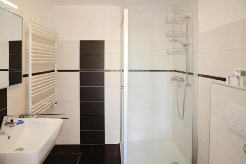 ein weißes Bad mit einer Dusche und einem Waschbecken in der Unterkunft Apartments home Wyk auf Föhr - DNS10067-SYA in Wyk auf Föhr