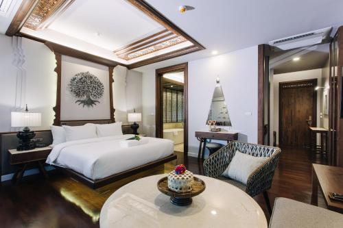 a bedroom with a bed and a table and a couch at T Heritage Hotel in Chiang Mai