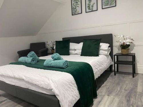 a bedroom with two beds with green and white sheets at Comfortable and Modern 2-Bedroom Flat in Bridgend in Bridgend