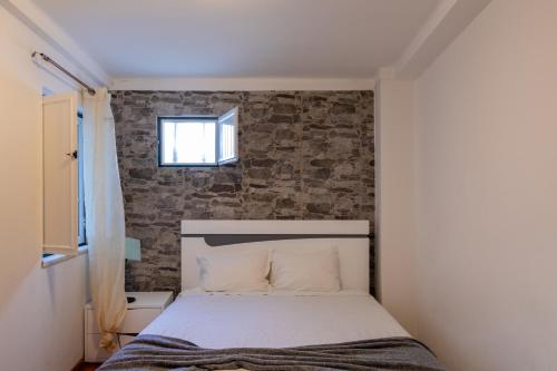 a bed in a room with a brick wall at Casas do Megué in Évora