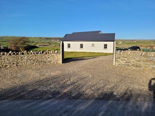 a white house with a stone wall and a driveway at Aiteall Bed and Breakfast in Liscannor