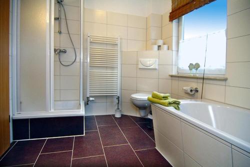 a bathroom with a tub and a toilet and a sink at Holiday home Kiebitz, Plau am See in Plau am See