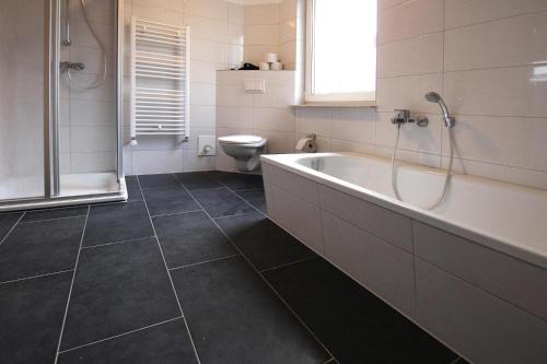 a bathroom with a bath tub and a toilet at Holiday home Kiebitz, Plau am See in Plau am See