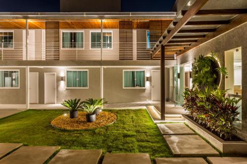 a courtyard of a building with grass and plants at Pousada Boutique do lazer in Cabo Frio