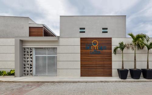 a building with a garage and palm trees in front of it at Pousada Boutique do lazer in Cabo Frio