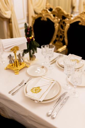 a white table with white plates and silverware on it at Royal Palace Luxury Hotel and SPA in Khmelʼnytsʼkyy