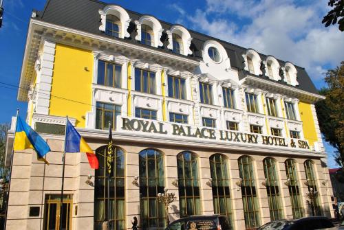 ein gelbes und weißes Gebäude mit Flaggen davor in der Unterkunft Royal Palace Luxury Hotel and SPA in Chmelnyzkyj
