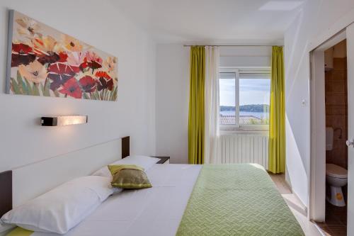 a bedroom with a large white bed with a window at Apartments Juric in Rab