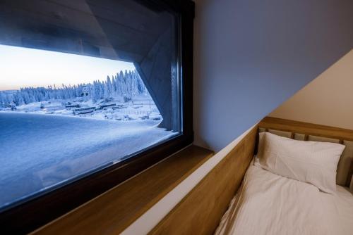 a bedroom with a large window with a winter view at Apartments Suncani Vrhovi Kopaonik in Kopaonik