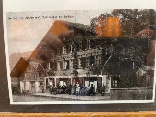 an old picture of a building with people in front of it at Haus Bergmann in Boltigen