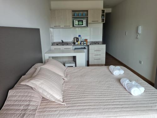 a bedroom with a bed with two pillows and a kitchen at Aires de Capital Depto in Salta