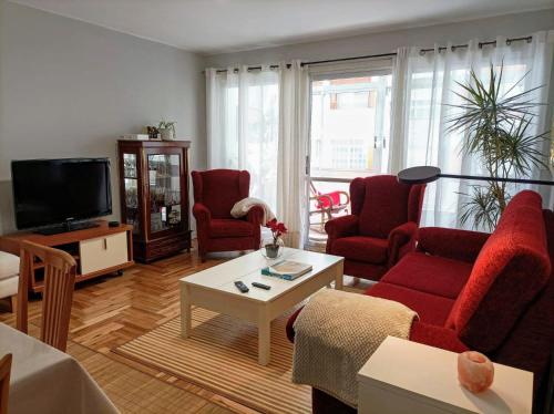 a living room with red chairs and a flat screen tv at Casa Porto, con Garaje in Vigo