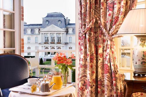 een tafel met een vaas met bloemen en een raam bij Château D'artigny in Montbazon