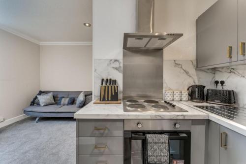 a kitchen with a stove top oven next to a couch at The Garden Flat, Loch Lomond in Alexandria