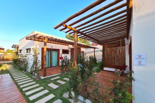 a house with a wooden deck with a pergola at Kai'ala Pousada in São Miguel do Gostoso
