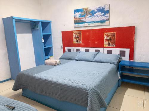 ein Schlafzimmer mit einem blauen Bett und einer roten Wand in der Unterkunft Casa Mediterraneo in Chamela