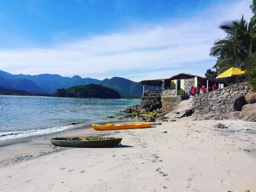 three canoes on a beach next to the water at A VER O MAR FLATS in Caraguatatuba