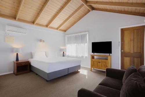 a bedroom with a bed and a flat screen tv at The Great Ocean Road Studios in Port Campbell