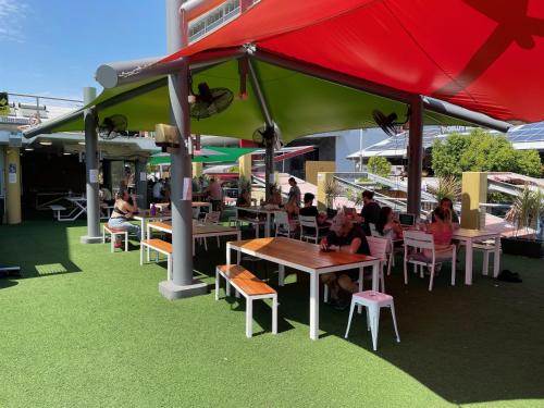 a group of people sitting at tables under a red umbrella at MOM Darwin in Darwin