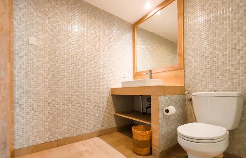 a bathroom with a toilet and a sink and a mirror at Core Hotel Benoa in Nusa Dua
