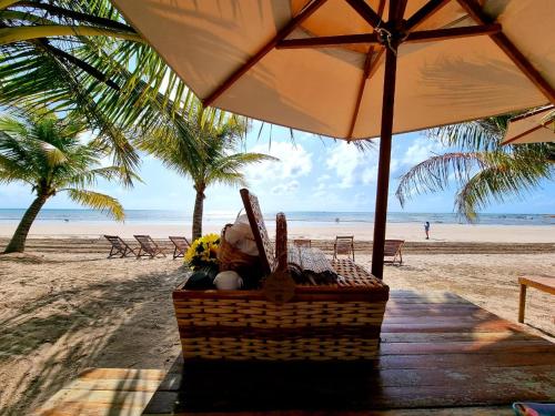 uma cesta de piquenique na praia debaixo de um guarda-sol em Pousada Enero em Maragogi