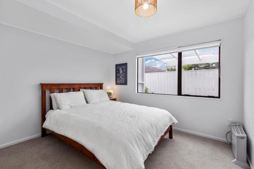 een slaapkamer met een groot bed en een raam bij Orewa Estuary Retreat - Orewa Downstairs Unit in Orewa
