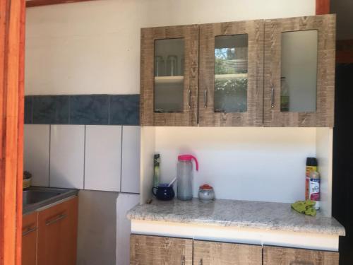 a kitchen with white cabinets and a counter top at Cabaña en San Javier de Loncomilla, in Linares