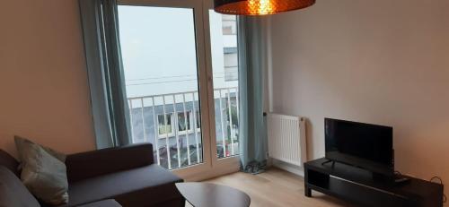 sala de estar con sofá y ventana grande en Cozy City Apartment, en Düsseldorf
