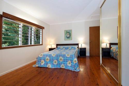 a bedroom with a bed with a blue comforter and a window at Private Rainforest Ridge Retreat in Kuranda