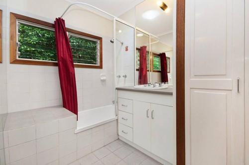 a white bathroom with a shower and a sink at Private Rainforest Ridge Retreat in Kuranda