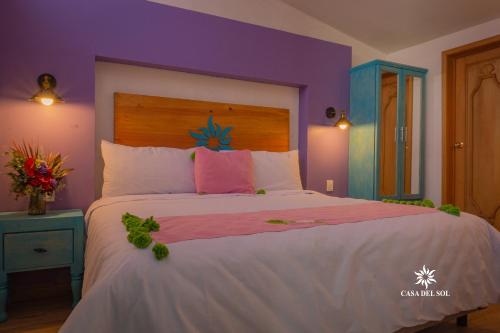 - une chambre avec un grand lit aux murs violets dans l'établissement Hotel Casa del Sol, à San Cristóbal de Las Casas