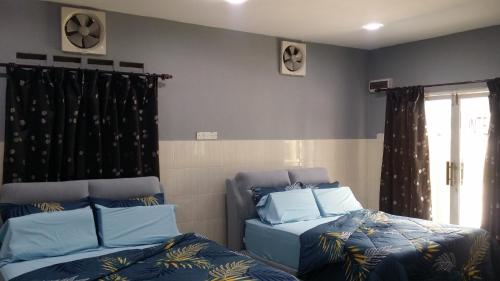 a room with two beds and a window at Kuntum Cottage Bed & Breakfast in Kampong Tanjong Ipoh
