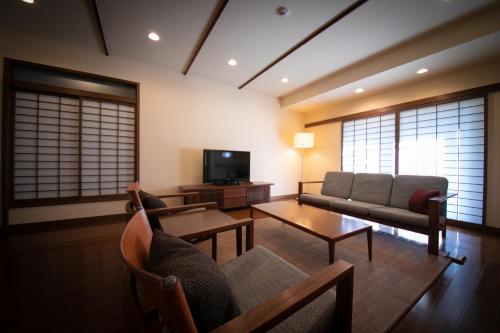 a living room with a couch and a tv at Yufuin Bettei Itsuki in Yufuin