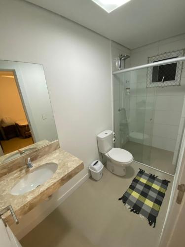 a bathroom with a sink and a toilet and a mirror at Ed. Mauí, 2 suítes, divisa Capão e Atlântida in Capão da Canoa