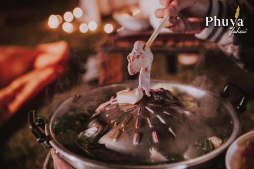 a person stirring food in a pot with a wooden spoon at Phuyafahsai The Resort Khao Kho in Khao Kho